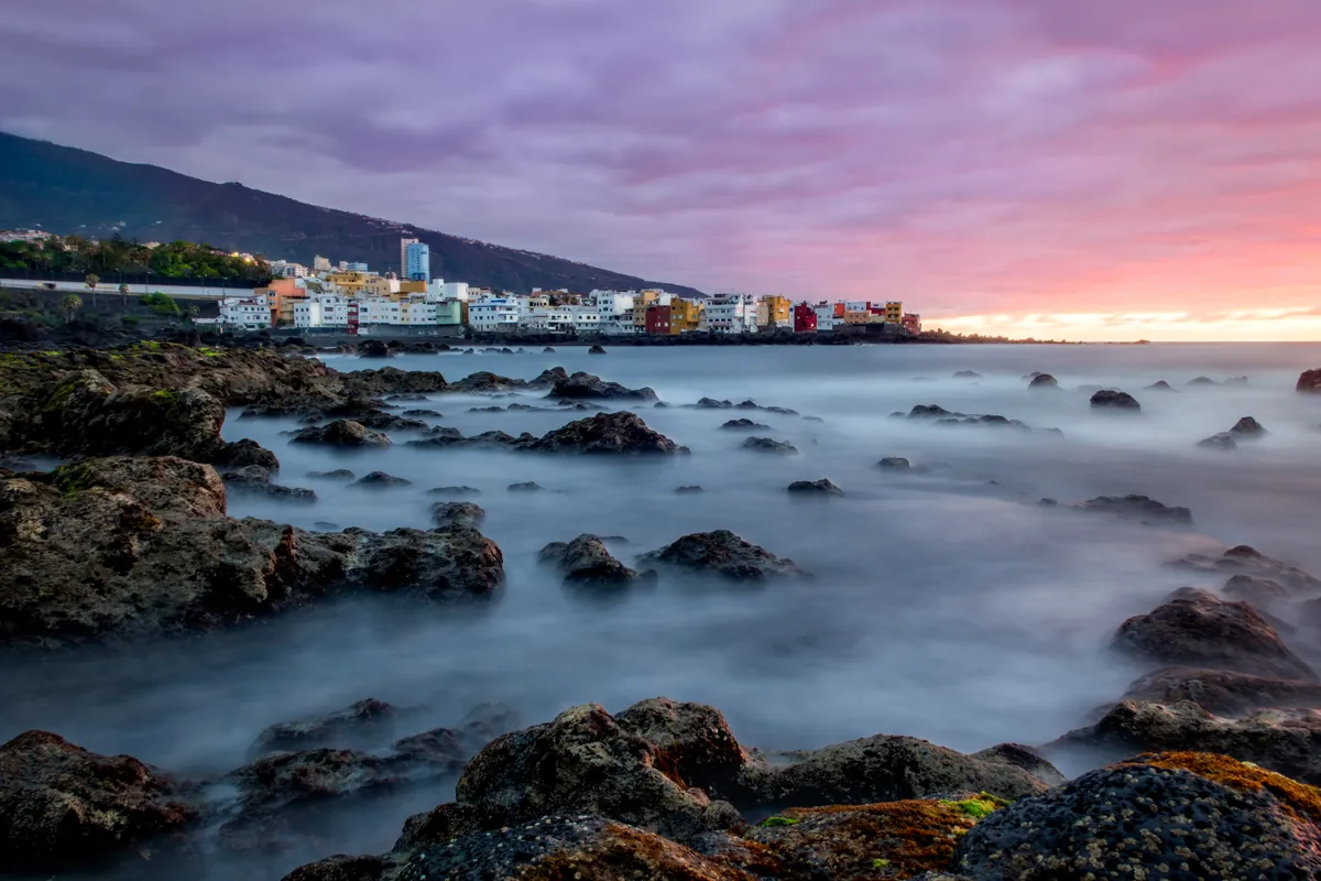 Rocky Tenerife coastline at sunset with a purple sky