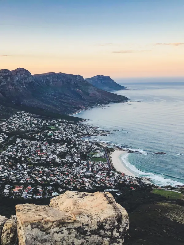 Aerial view of a Cape coastline with mountains, a seaside suburb and a curved beach at dusk